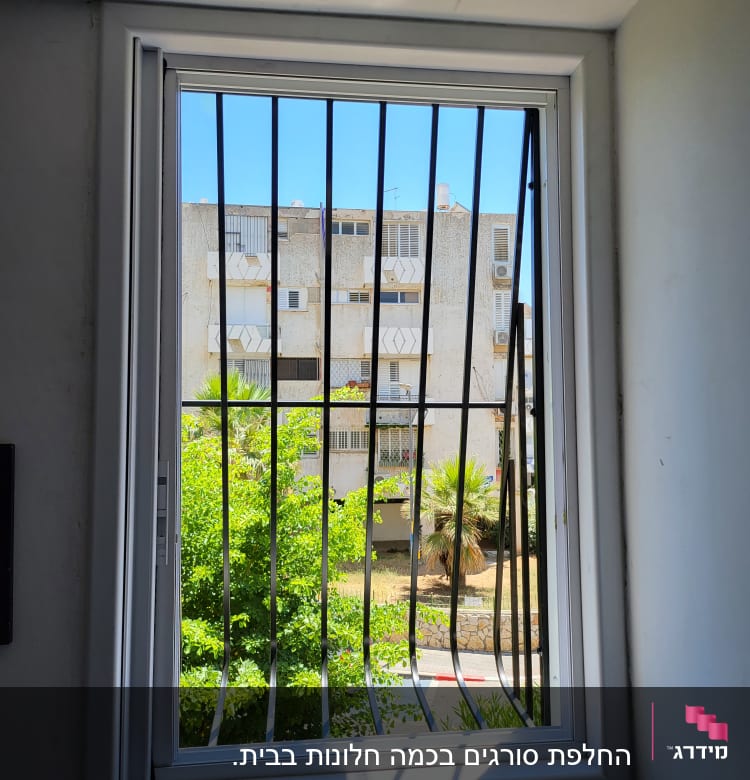 חלון עם סורגים שחורים במסגרת לבנה